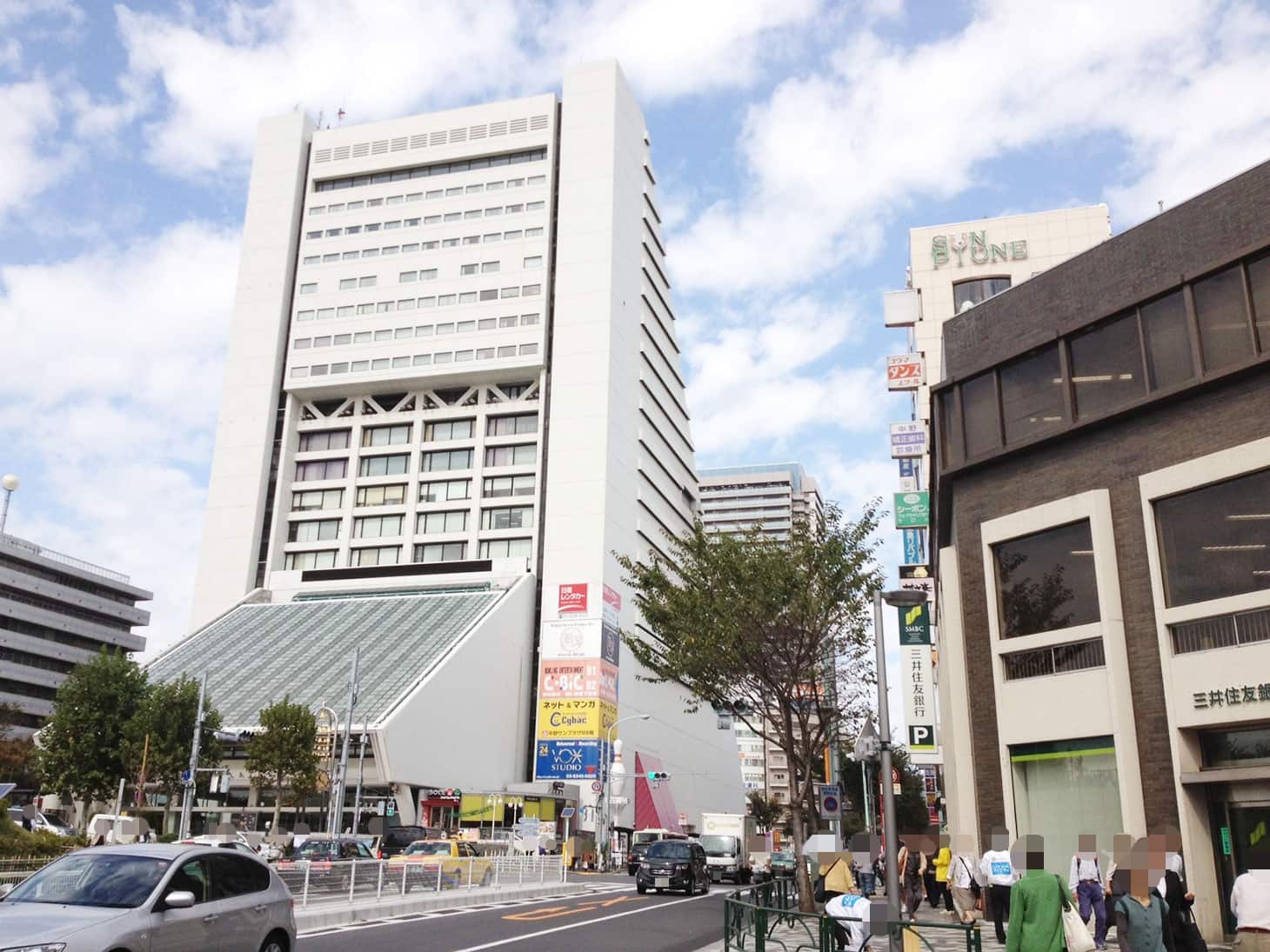 ロータリーを渡り、三井住友銀行の左側の道路に沿って進んで下さい。