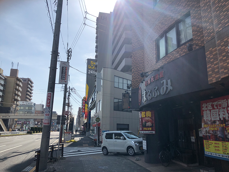 しばらくすると右手に居酒屋が見えます。横断歩道を渡ると右手に店舗が見えます。